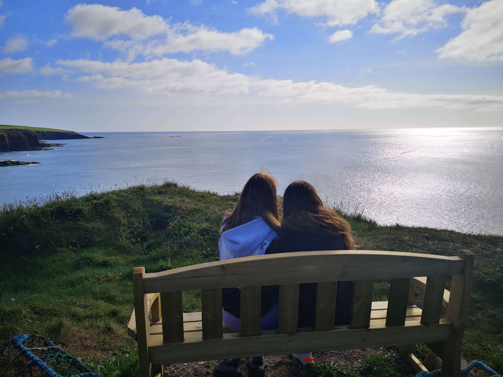 Girls sitting on bench looking at the sea