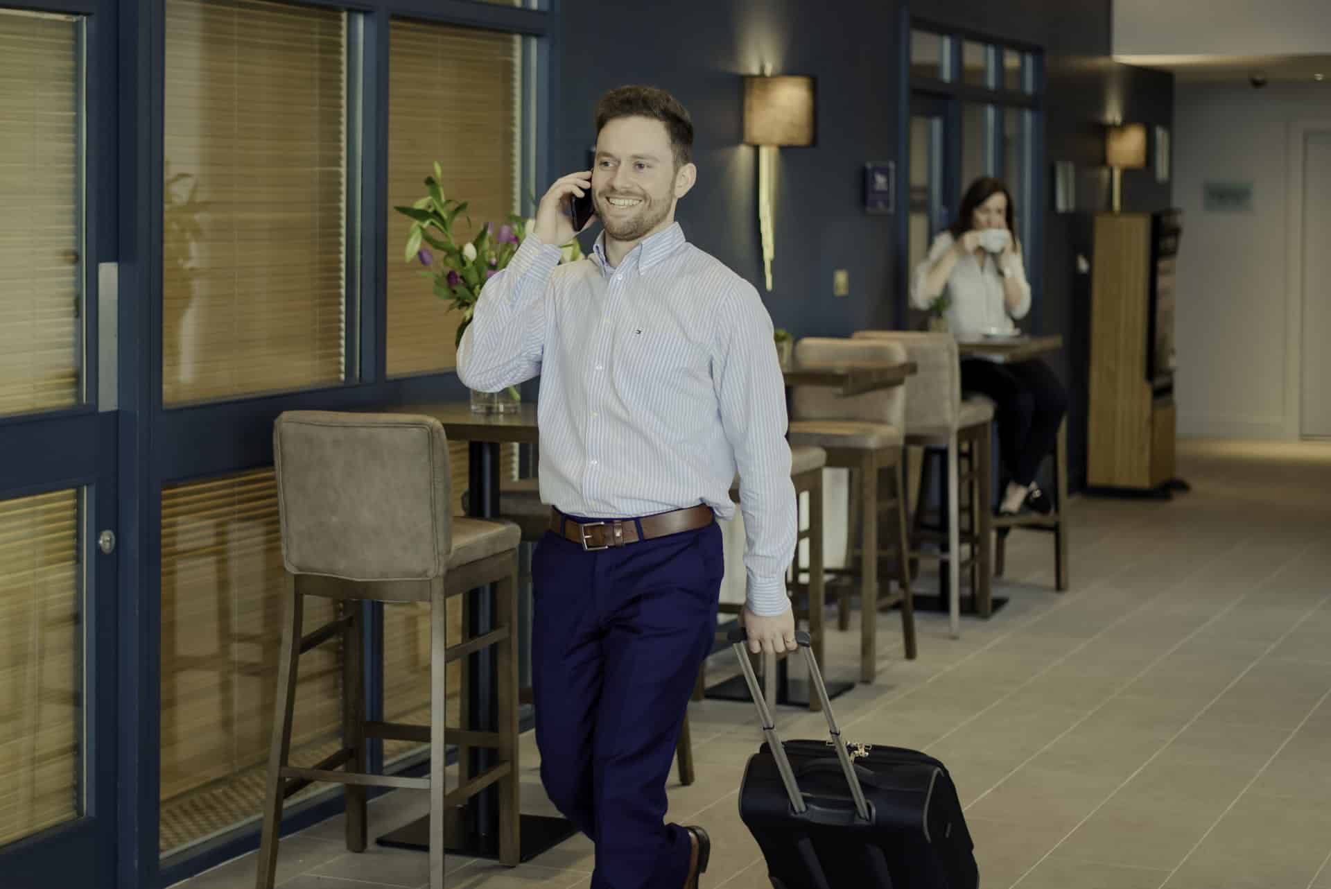 Viking Hotel Waterford businessman walking through lobby with suitcase and lady in background