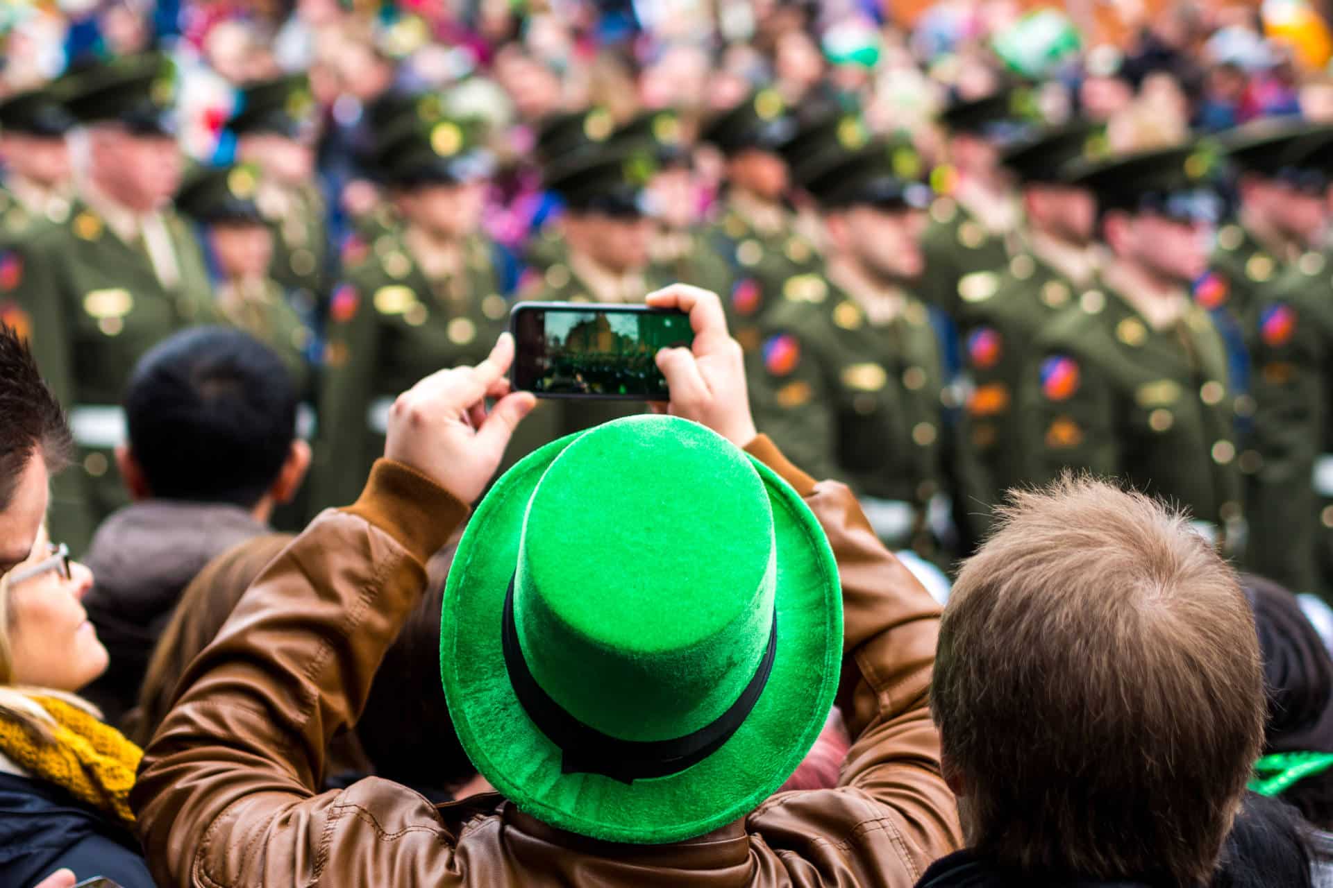 Man in St.Patricks Day hat taking an image of the parade