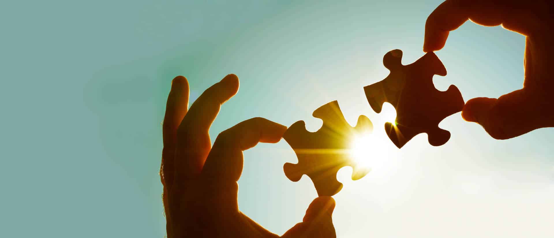 Two people holding piece of puzzles to signift partnerships