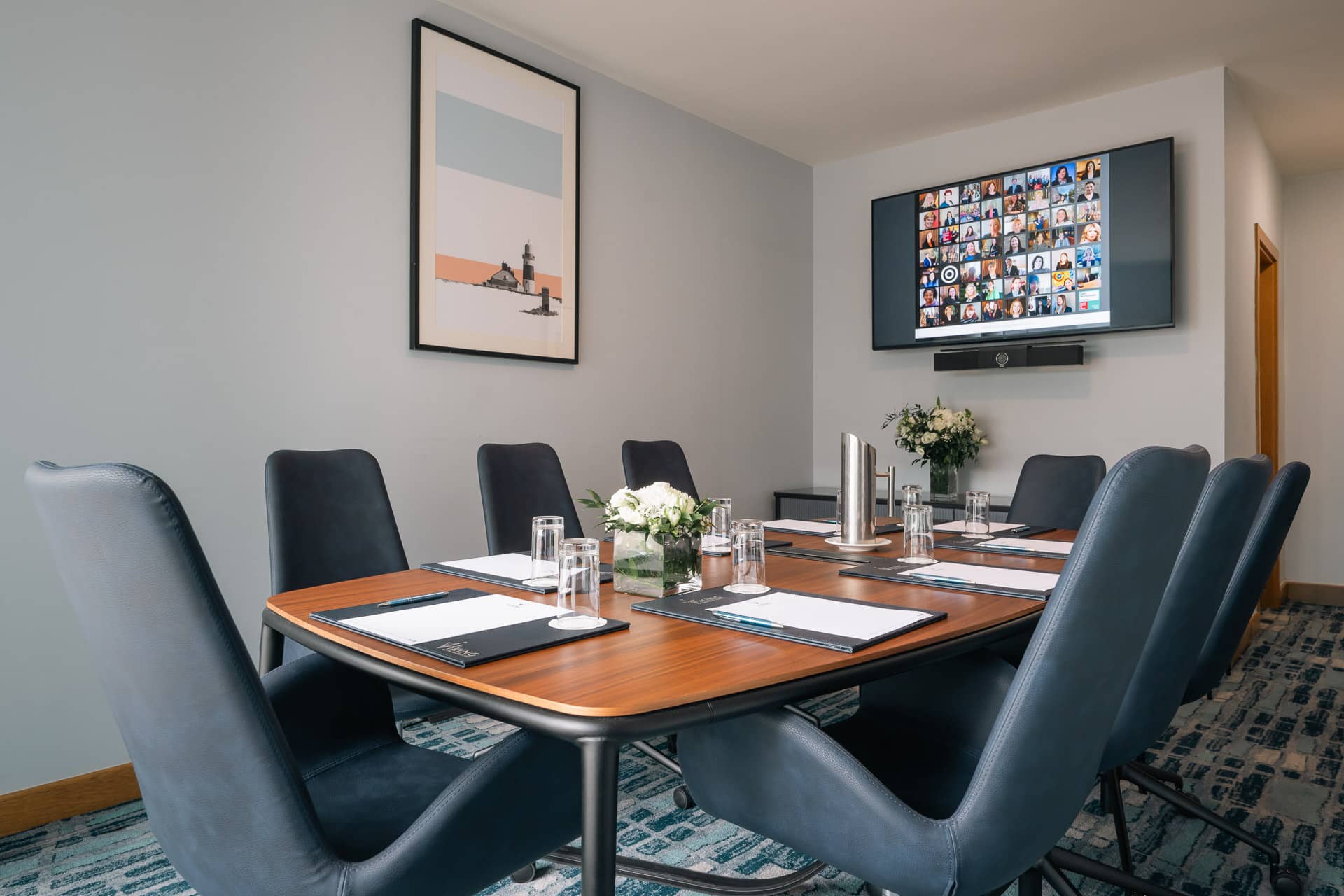 Boardroom-style meeting room at Viking Hotel Waterford with eight leather chairs, a wooden table set with notepads and water glasses, a wall-mounted TV for video conferencing