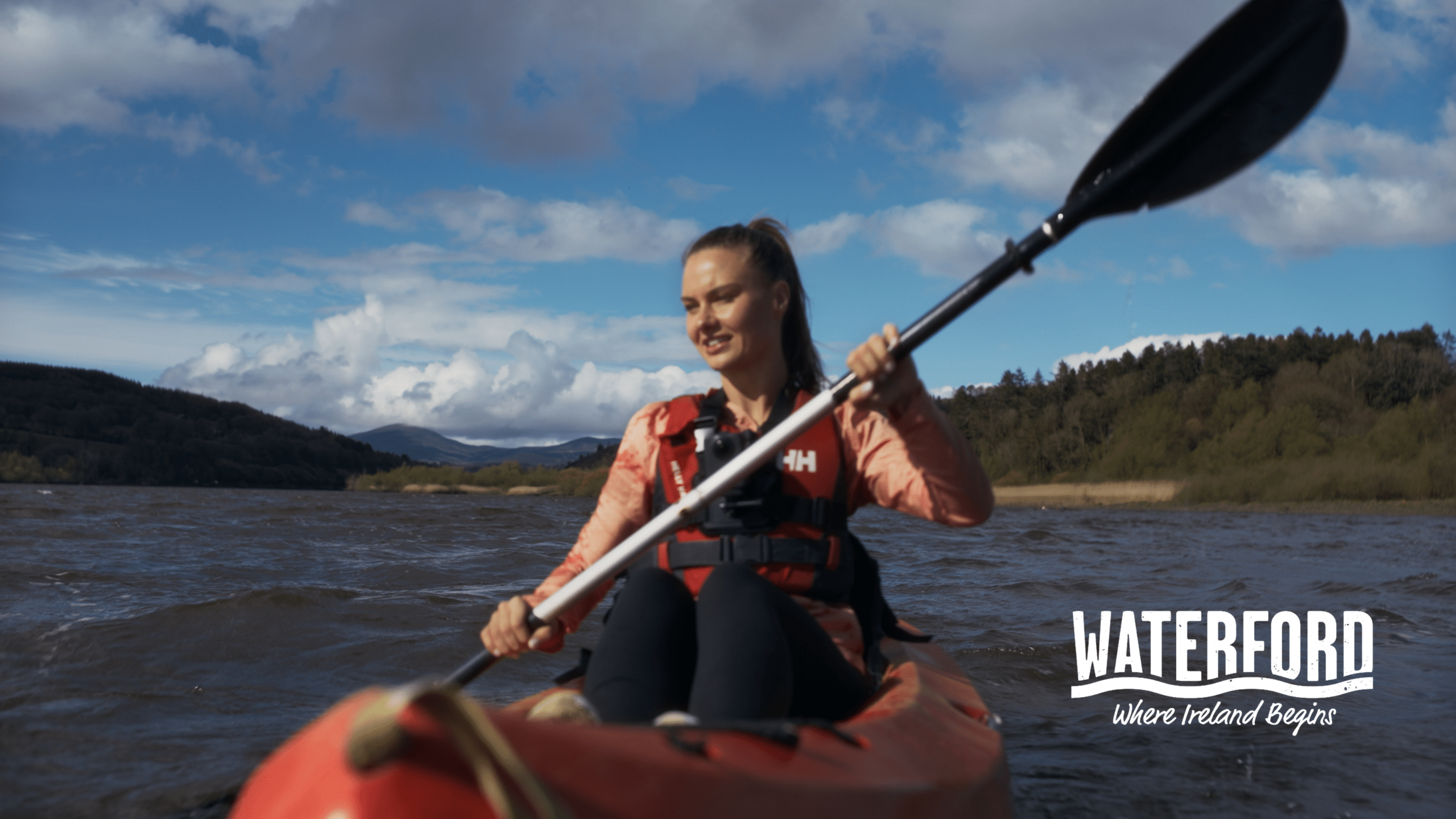 Girl paddleing in a canoe, The canoe is red and she is holding an oar in Waterford